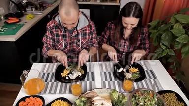 夫妻俩坐在餐桌旁的厨房里吃晚饭。 桌子上有<strong>沙拉</strong>、<strong>蔬菜</strong>、<strong>蔬菜</strong>、<strong>鸡肉</strong>、玉米